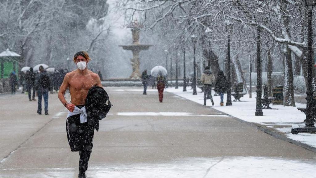 Un hombre corre por El Retiro de Madrid durante la nevada de este jueves.
