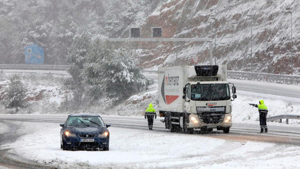 Un coche y un camión varados en una carretera cubierta por nieve.