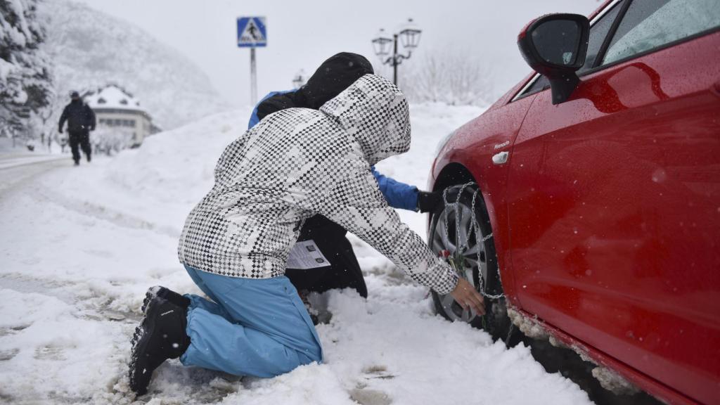 Personas poniendo unas cadenas al coche.