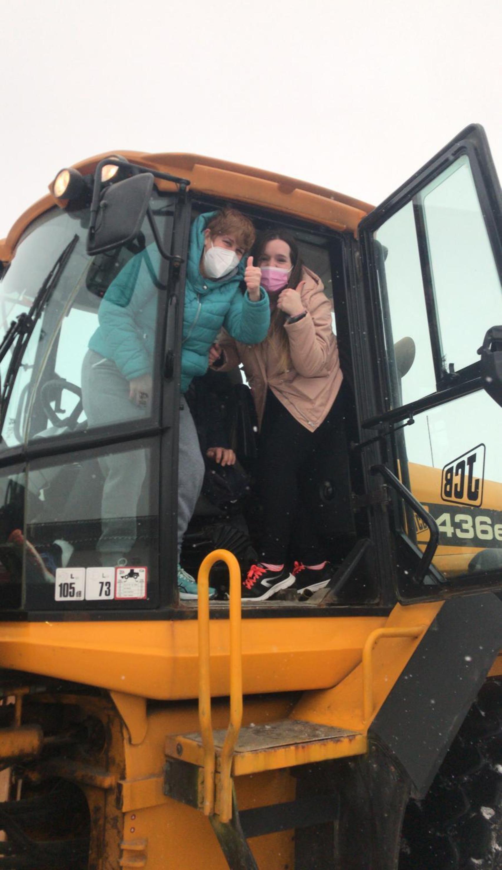 Dos trabajadoras de la Residencia Villa de La Seca (Valladolid) en la excavadora que las llevó hasta su centro de trabajo.