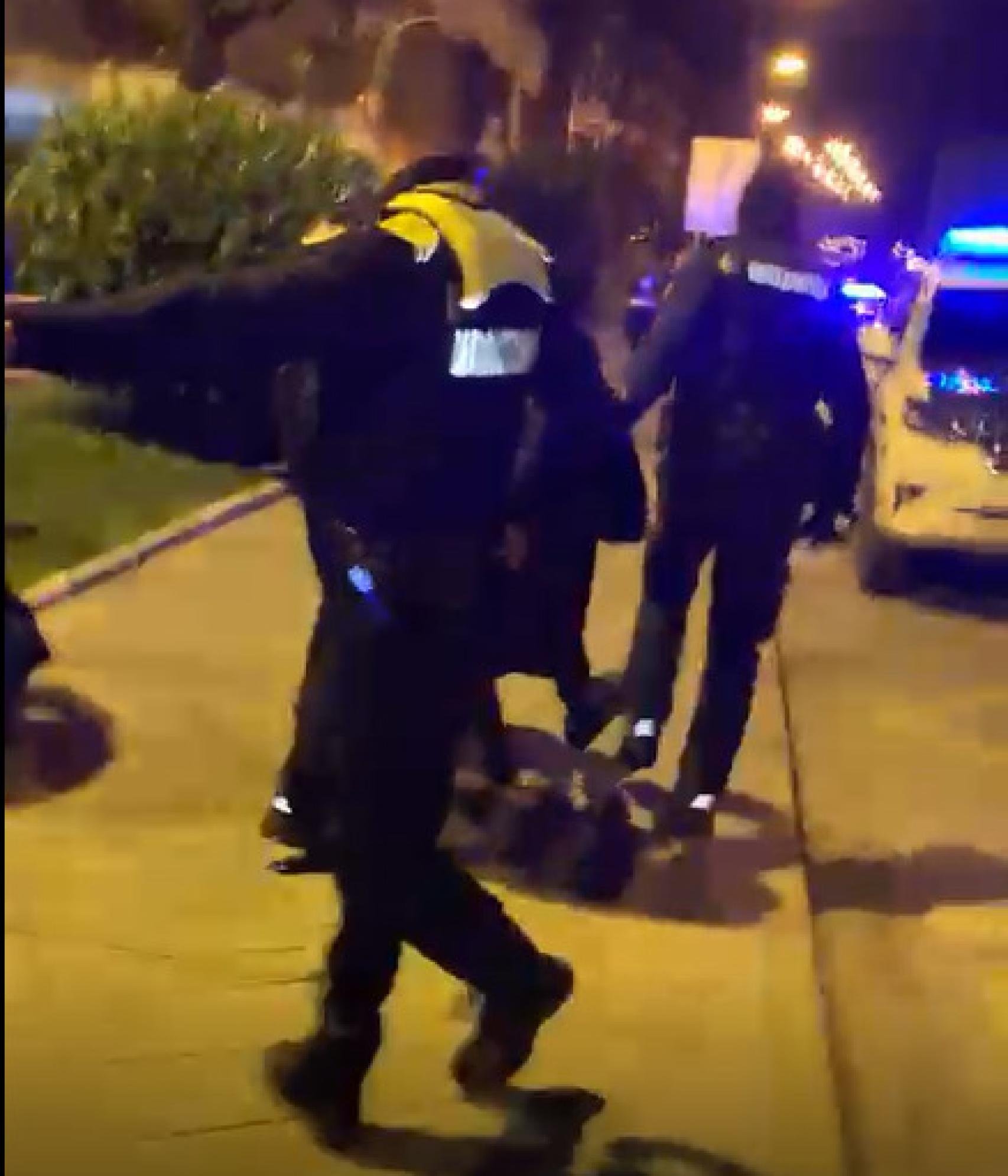 Un policía local de Munguía trata de retener a los jóvenes iracundos mientras sus compañeros conducen a un detenido a un coche patrulla.