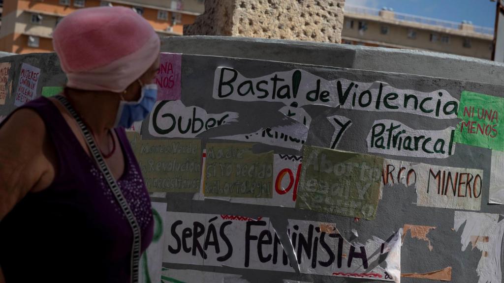 Una mujer camina frente a una pared con varios mensajes a favor del aborto en Caracas.