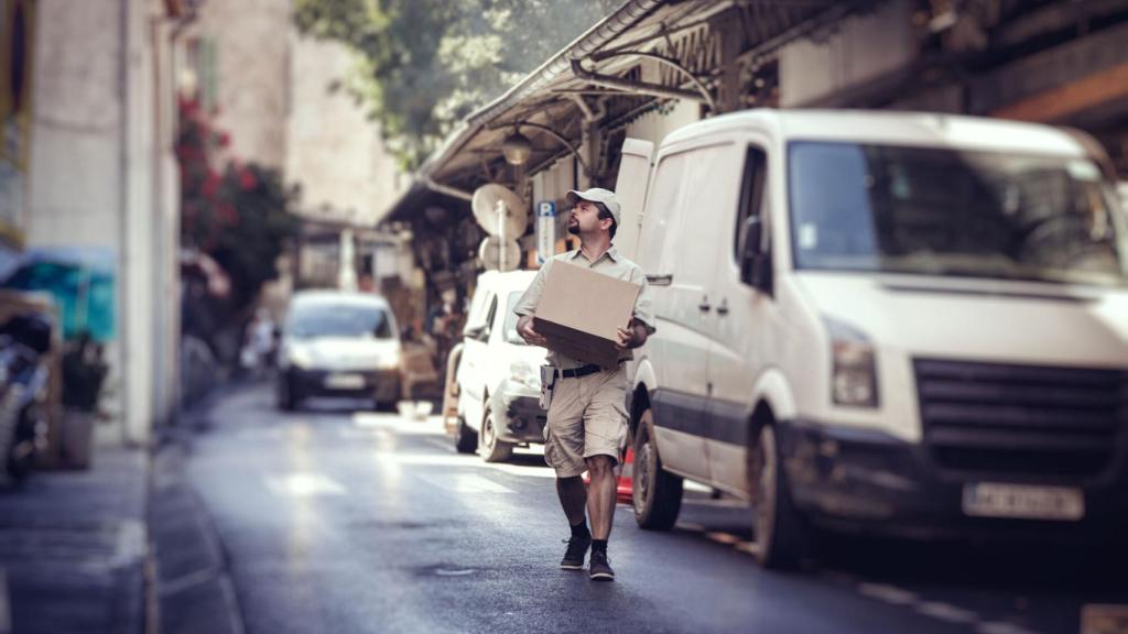 Una calle con diferentes furgonetas de reparto y un repartidor.