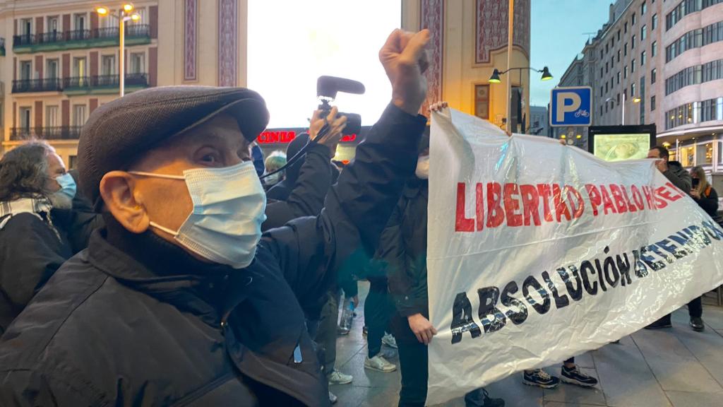 Un hombre levanta el puño junto a la pancarta de la manifestación.