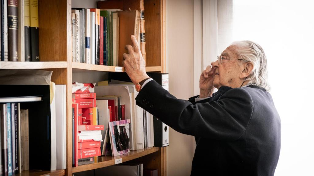 Miguel Doménech busca un libro en su biblioteca.