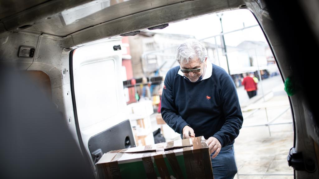 Oubiña descarga los fardos de ropa de su furgoneta.