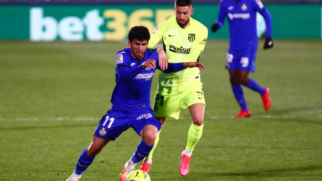 Carles Aleña lucha en carrera con Yannick Carrasco por el balón