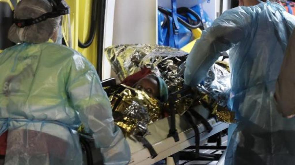 Uno de los niños hospitalizados, en una camilla accediendo a una ambulancia.