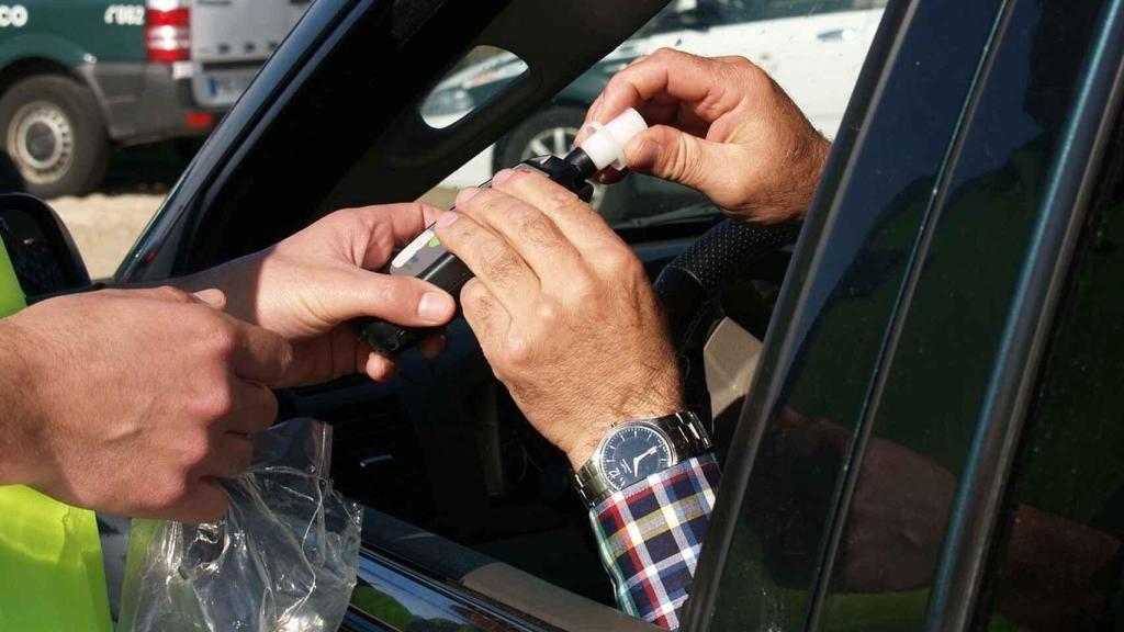 Un agente realizando un test de alcoholemia a un conductor.