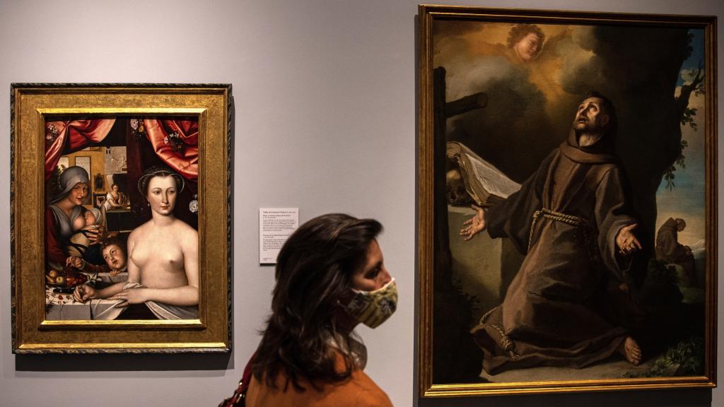 Una mujer pasa ante varias de las obras que forman parte la exposición del legado de Carmen Sánchez.