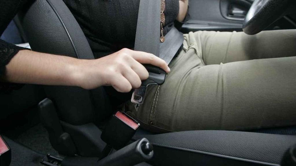 Una conductora se abrocha el cinturón de seguridad en su vehículo