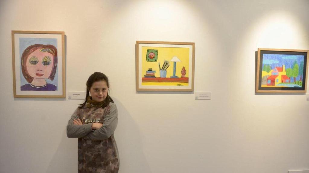 Andrea, junto algunos cuadros que ha pintado.