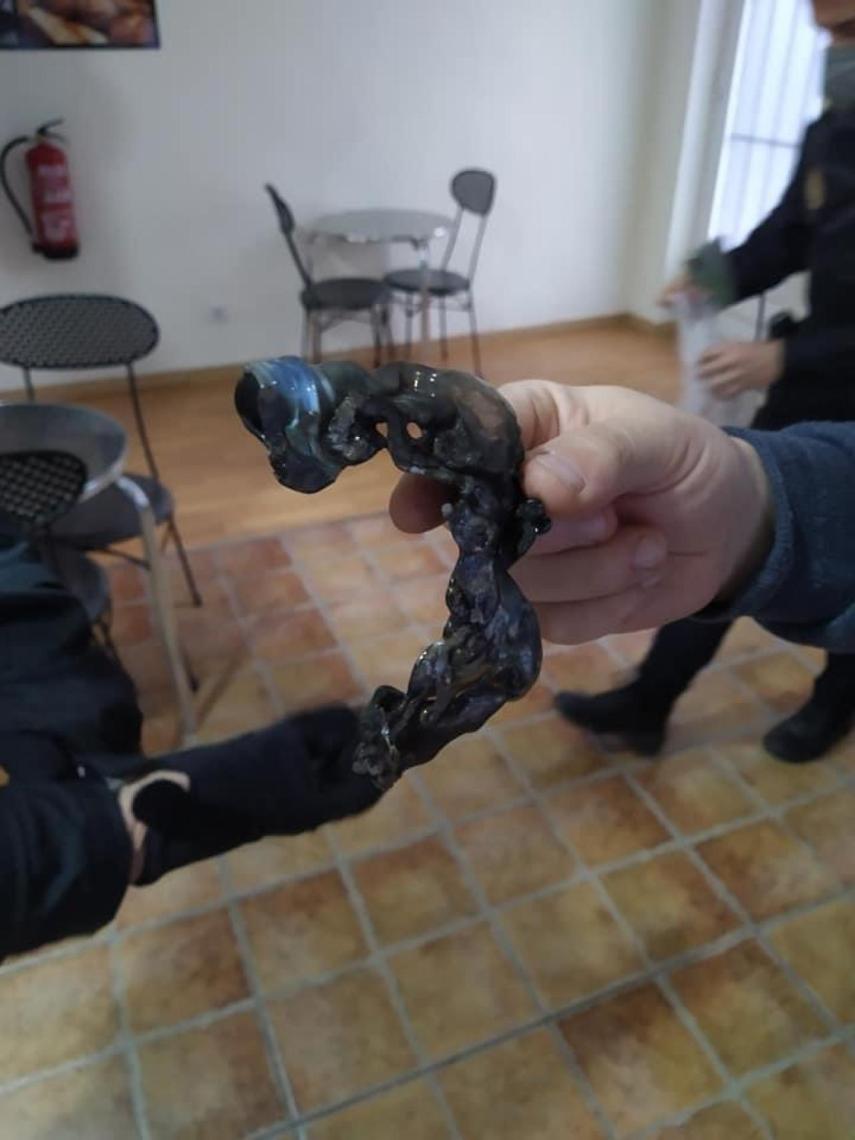 Un policía nacional sujetando los restos del cóctel  molotov.