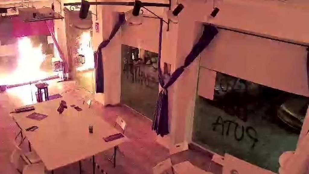 La fachada de la sede de Podemos en llamas tras el impacto del cóctel molotov.