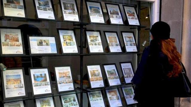 Una mujer mira ofertas de piso en una inmobiliaria.