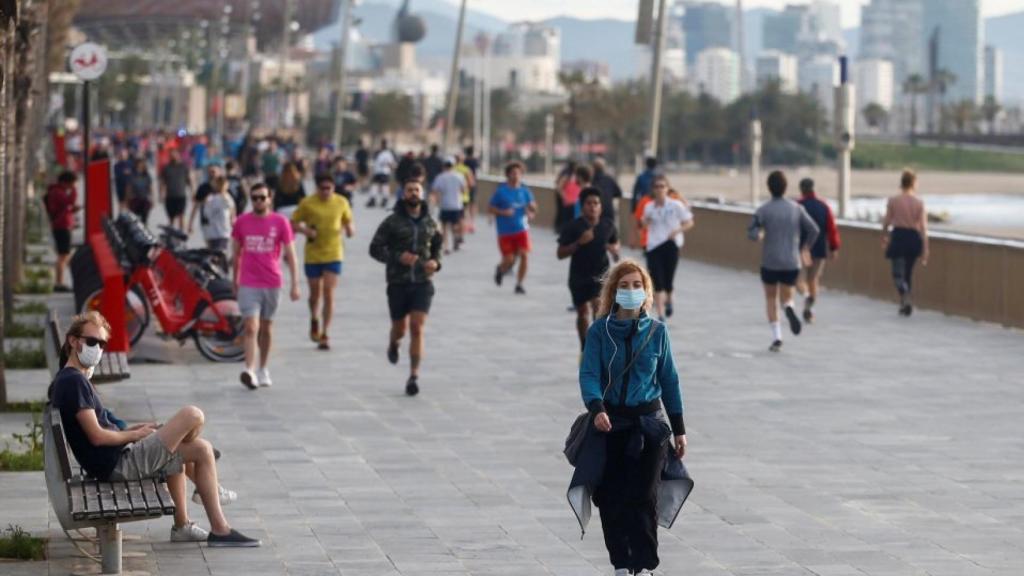 Gente con y sin mascarilla en un paseo marítimo.