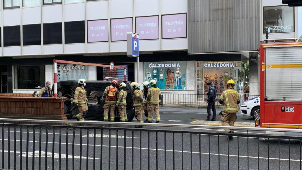 Varios bomberos estudian cómo proceder con el BMW volcado en la entrada del túnel