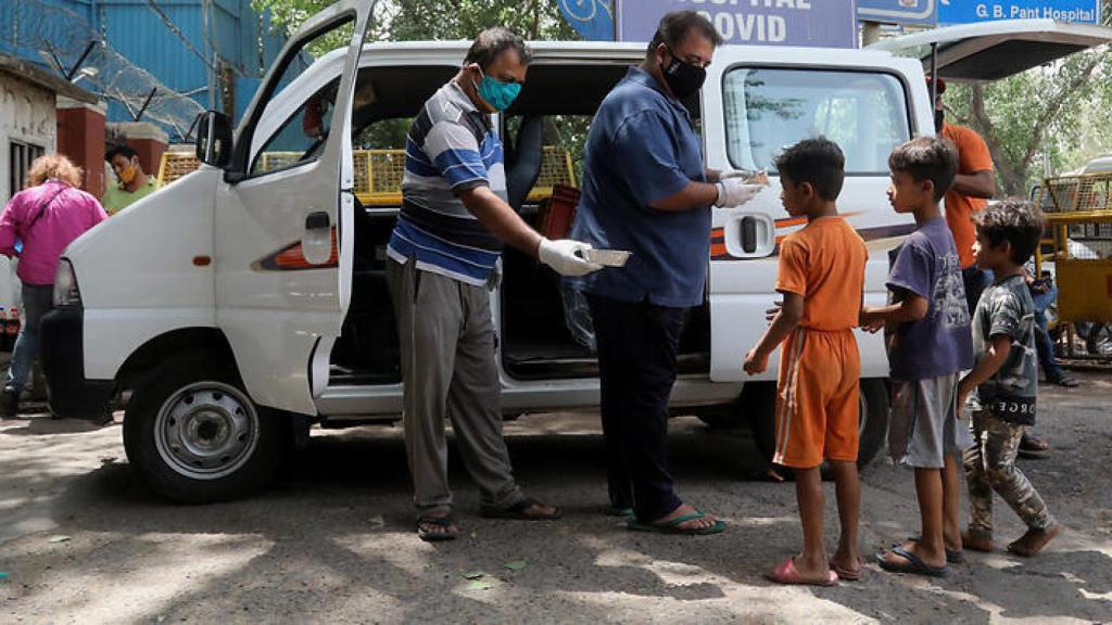 La gente distribuye comida a los niños fuera de un centro de cuidado en Shehnai (India).