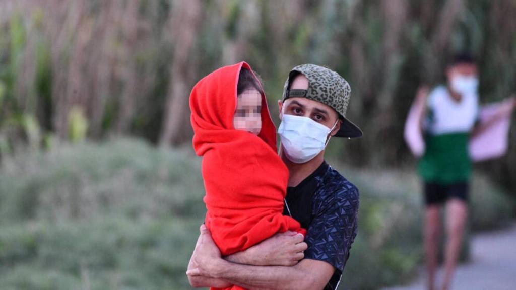 Un hombre migrante coge en brazos a una niña en la playa del Tarajal, a 17 de mayo de 2021, en Ceuta, (España). Foto: Europa Press