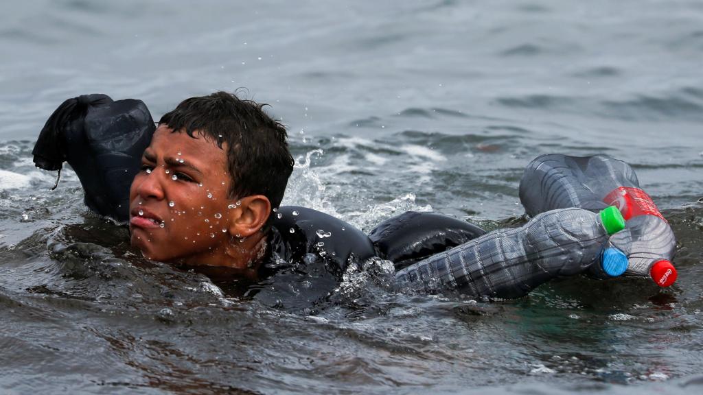 Un menor marroquí trata de alcanzar la playa de Ceuta.
