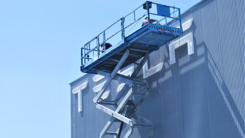 Operarios ultiman la fachada del primer centro de servicio de Tesla en Sevilla.