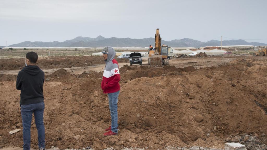 Dos habitantes de 'Walili' observan cómo remueven el terreno incenciado.