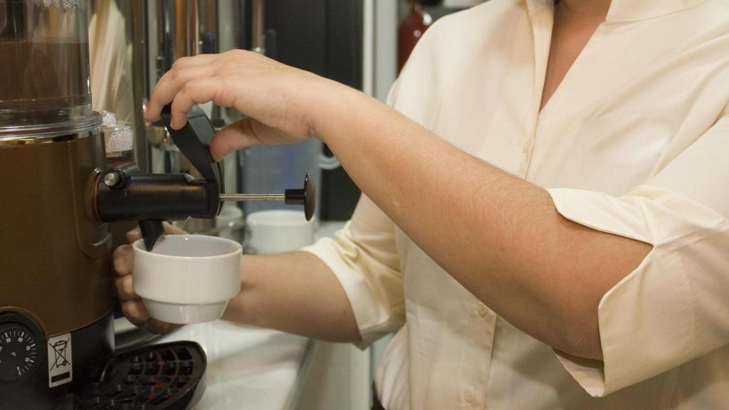El empleado de un establecimiento sirviendo un café.