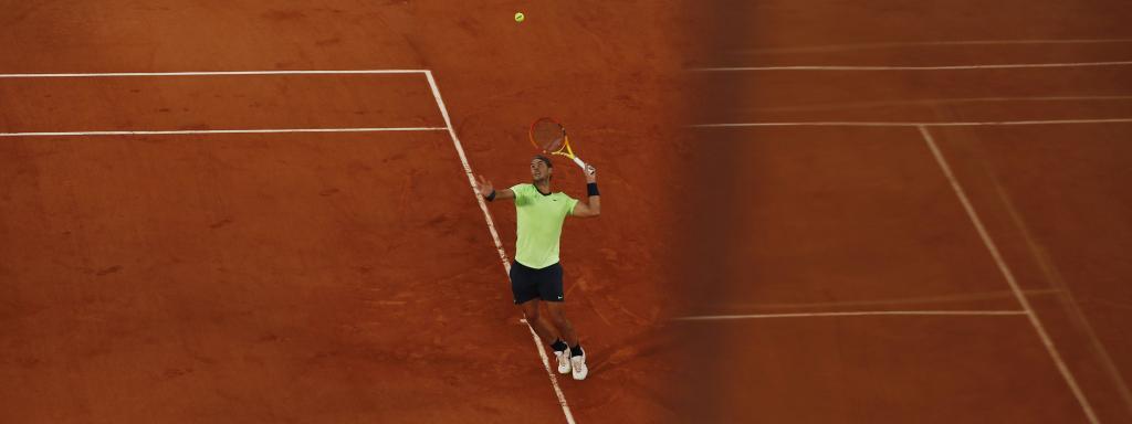 Nadal mientras saca de fondo en la tierra batida de Roland Garros