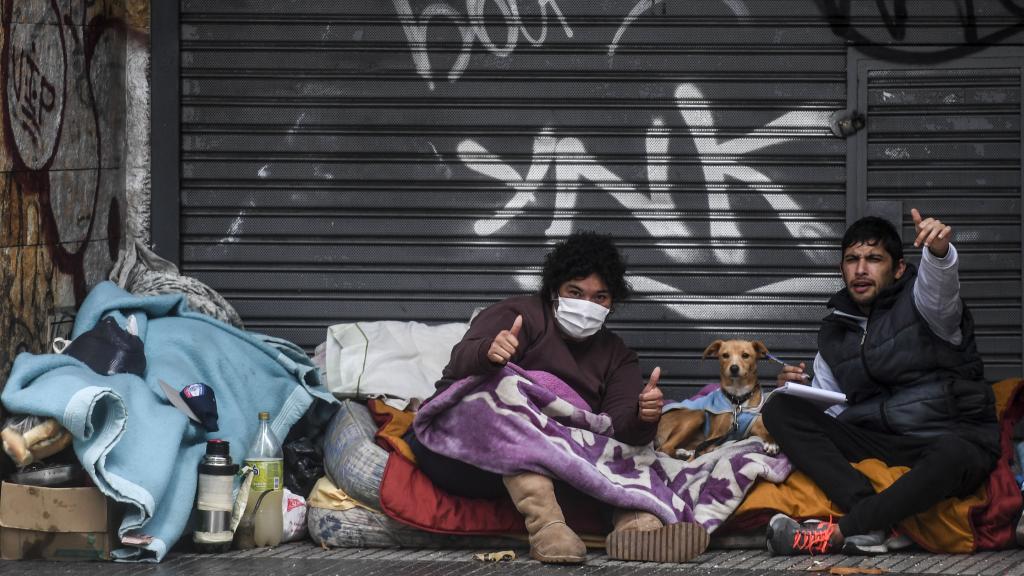 Dos personas que viven en la calle hacen gestos a la cámara.