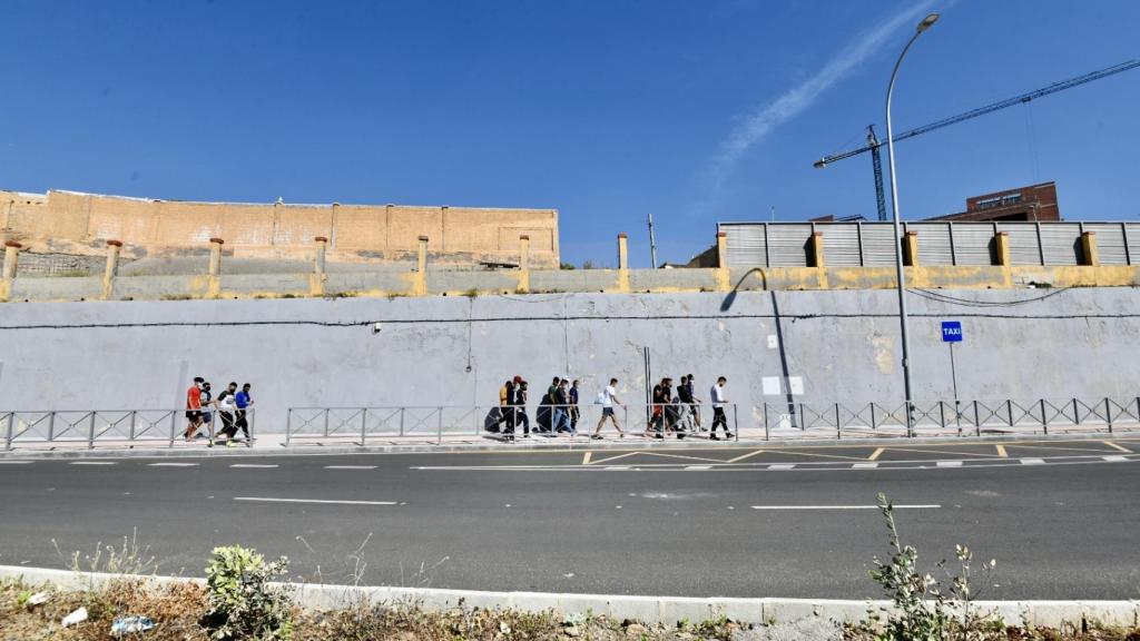 Varios migrantes procedentes de Marruecos hacen cola en las puertas de la frontera de Ceuta.