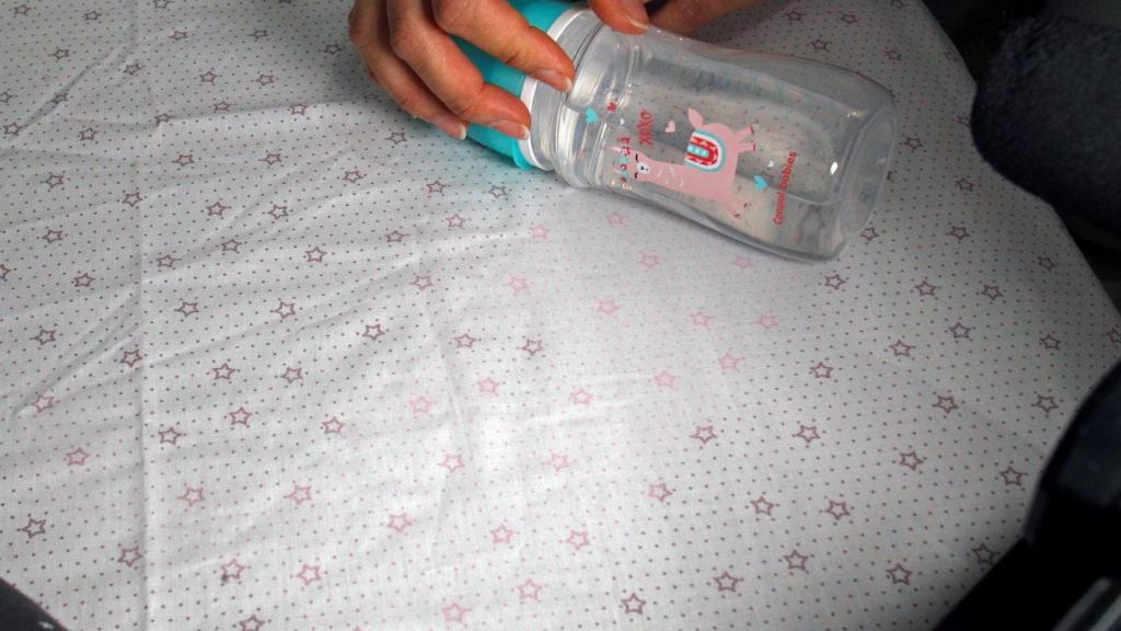 Detalle del textil, con un biberón al lado.