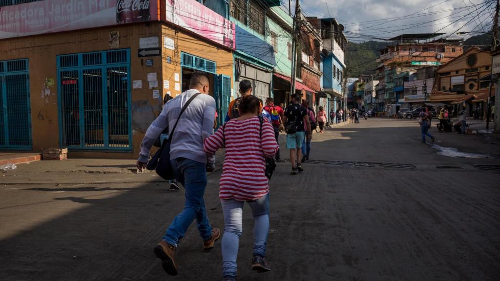 Un grupo de personas corre para cruzar una calle mientras suenan disparos en La Vega.