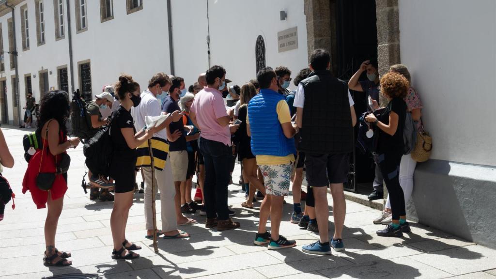 Peregrinos con mascarillas esperando su turno para entrar en el albergue.