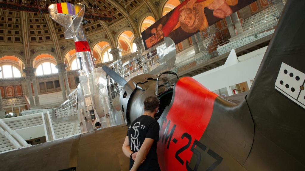 En primer plano, la reproducción del 'Mosca', con el bombardero 'Katiuska' suspendido del techo. Al fondo, detalle de la tabla 'La crucifixión de San Pedro'.