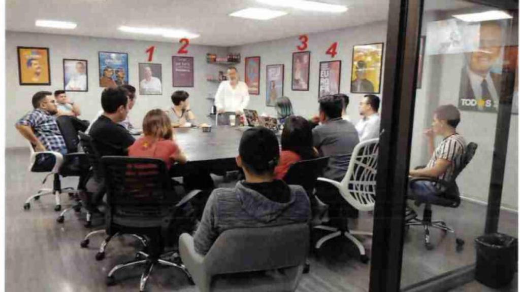 El máximo responsable de Neurona, César Hernández (de pie, en el centro), con varios carteles electorales de Podemos en su sala de reuniones.