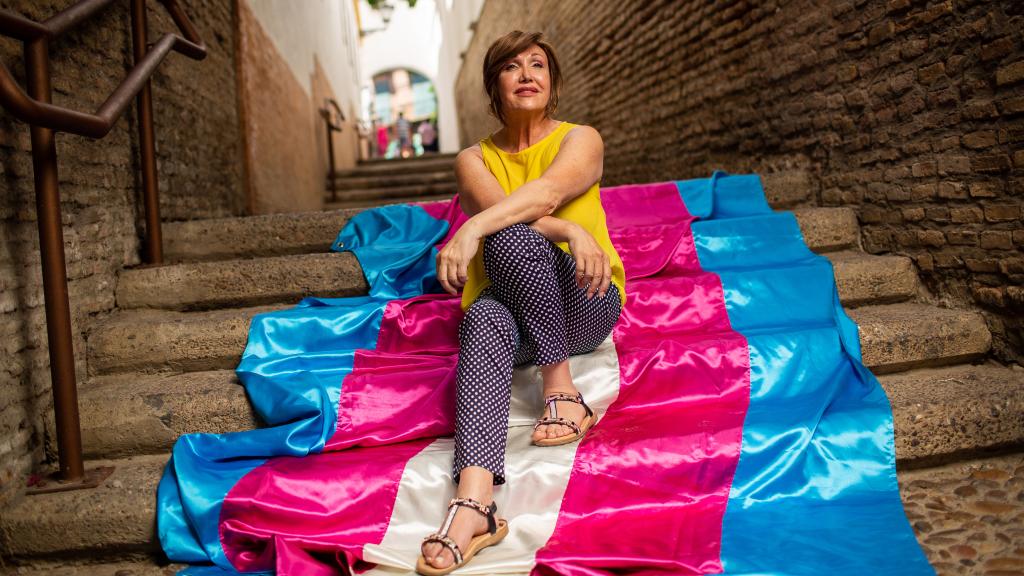 La presidenta de la Federación Plataforma Trans, Mar Cambrollé, posa en las escaleras con la bandera trans.
