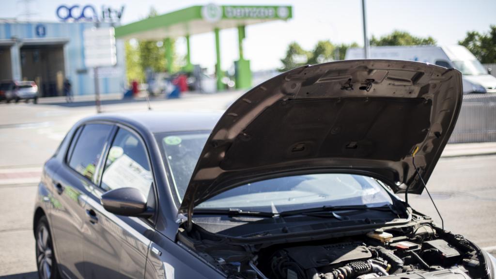 Un coche con el capó abierto frente a una estación de la Inspección Técnica del Vehículo.