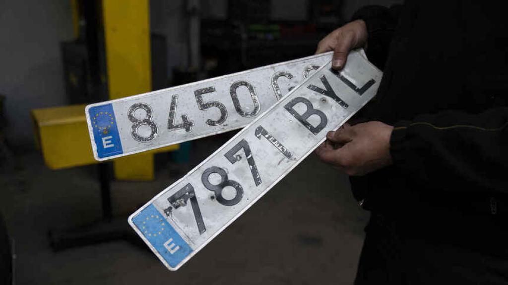 Un mecánico enseña dos matrículas que ha cambiado por no estar correctamente.