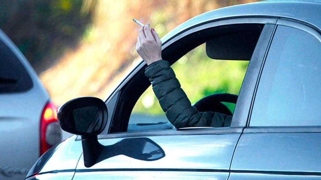 Una persona fumando mientras conduce.