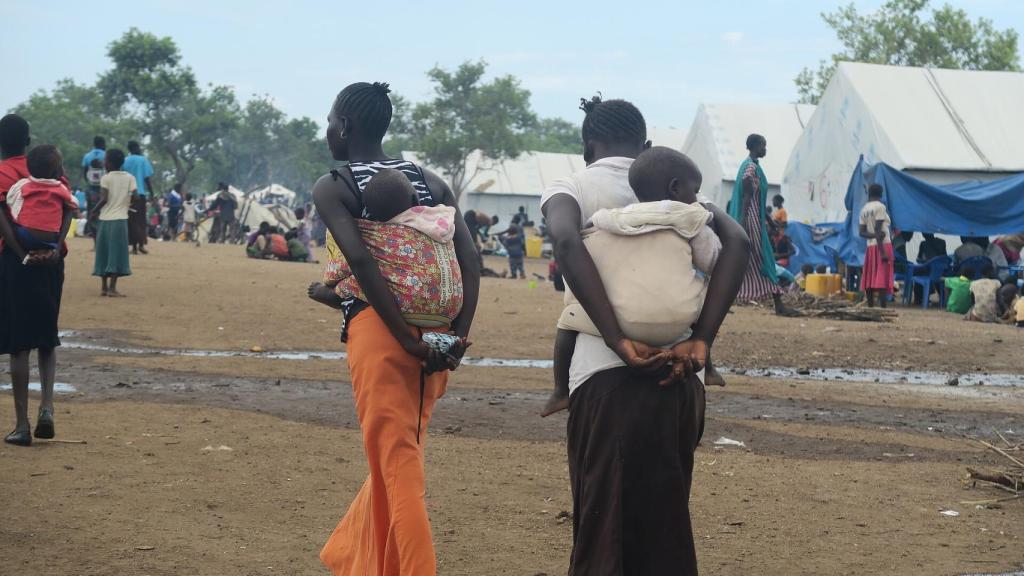 Dos mujeres llevan a la espalda a sus hijos.