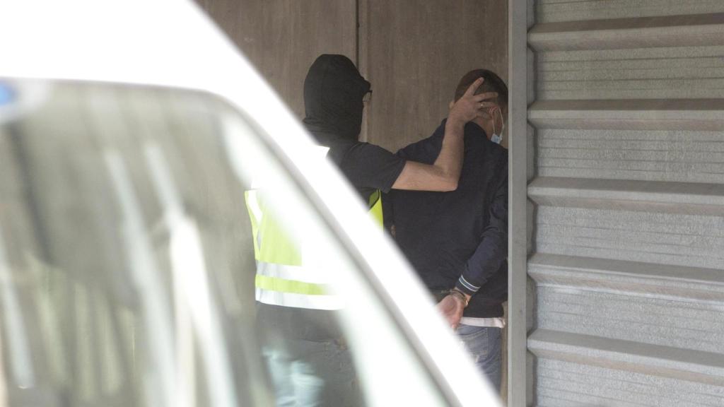 Un agente lleva arrestado a uno de los acusados para declarar.