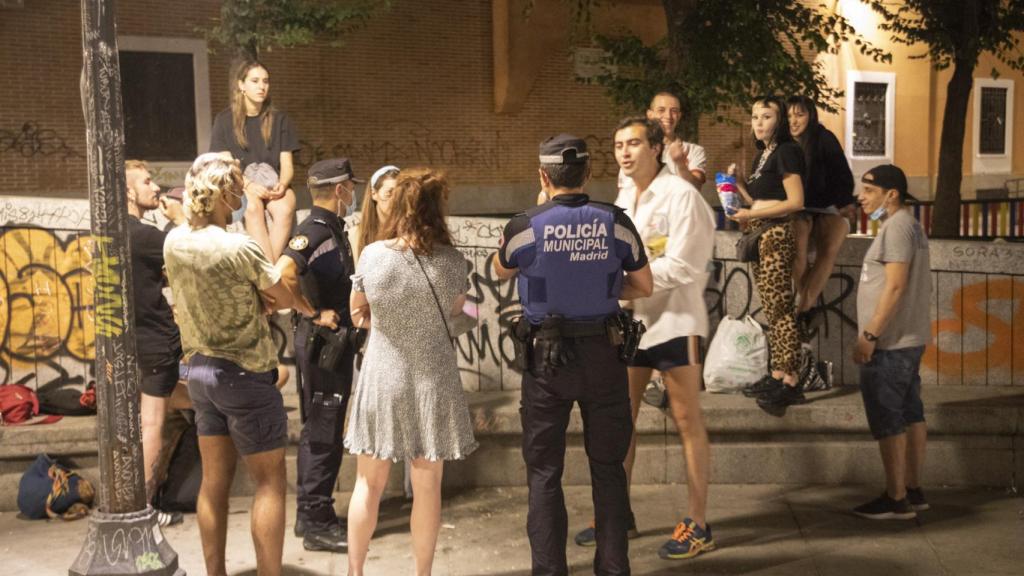 Dos agentes hablan con un grupo de gente, sin llegar a multarles.