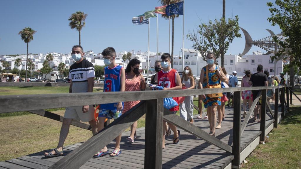 Unos niños bajan a la playa con las mascarillas puestas.