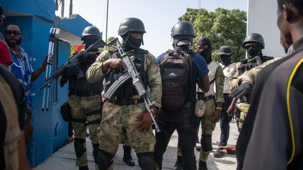 Policías custodian a un grupo de sospechosos de haber participado en el asesinato del presidente haitiano, Jovenel Moise.