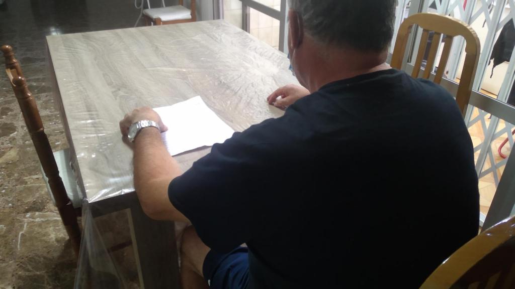 Paco, en el salón de su casa, repasando el parte de alta médica de su hijo.