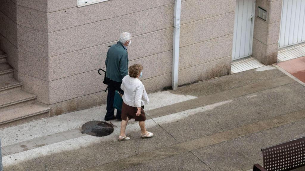 Dos viandantes intentando esquivar la lluvia en pleno julio