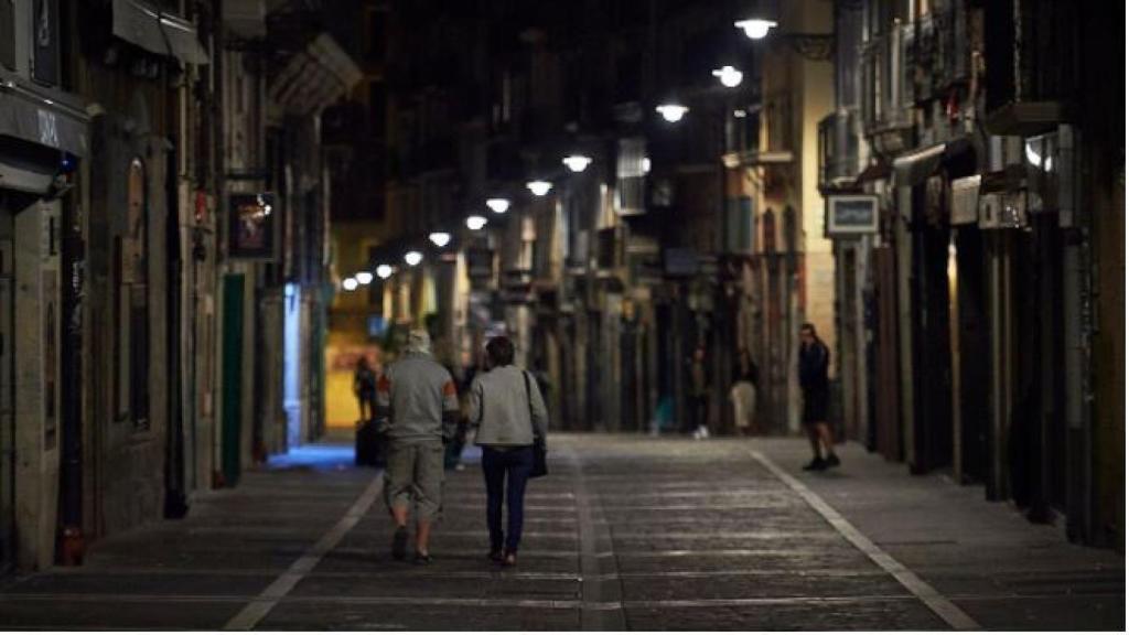 Varias personas caminan por una calle de Pamplona minutos antes del toque de queda.