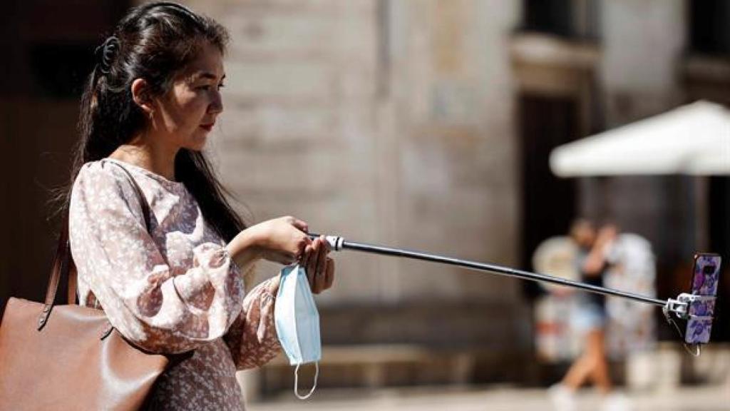 Una turista se hace una fotografía con el teléfono móvil este sábado en el centro de Valencia, durante el fin de semana en el que finaliza julio y da comienzo agosto, muchos empiezan sus vacaciones de verano y otros apuran sus últimos días