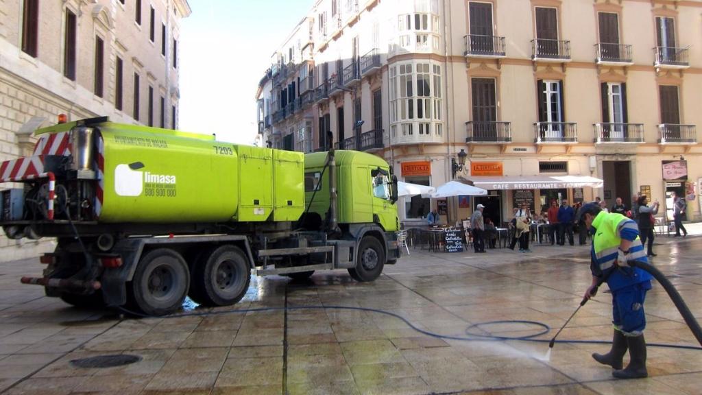 Un operario de Limasam baldea una calle en el Centro de Málaga.