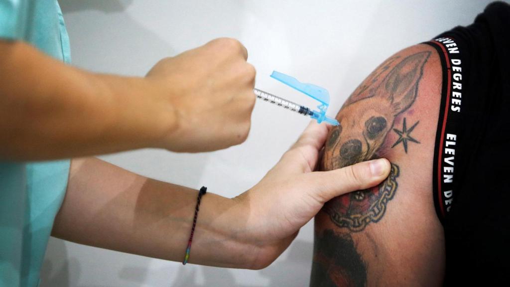 Una enfermera vacuna a un joven.